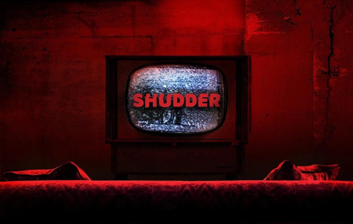 SHUDDER on TV screen in dark red room with couch