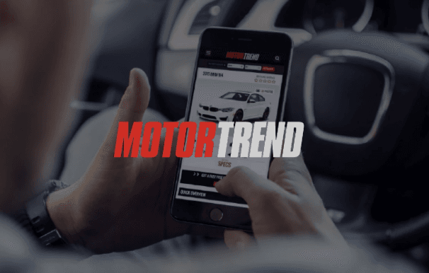 Person sitting in car on iPhone with MotorTrend logo